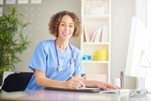 Smiling nurse at desk taking notes